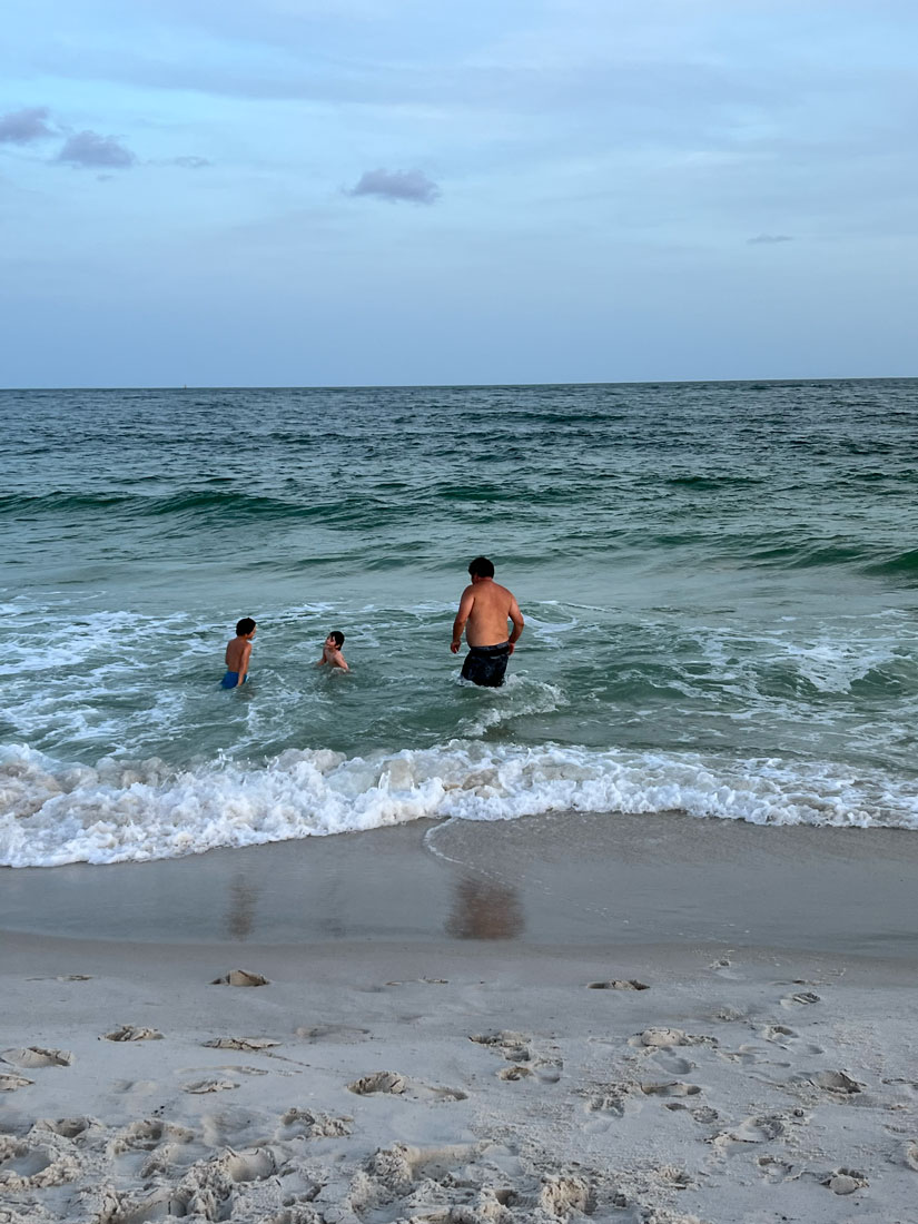 A father and his two sons jump into the ocean together